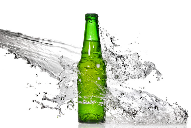 Green beer bottle with water splash isolated on white