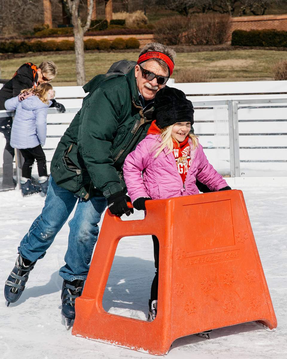 Fifty West Brewing ice skating rink dad helping child learn to skate 2