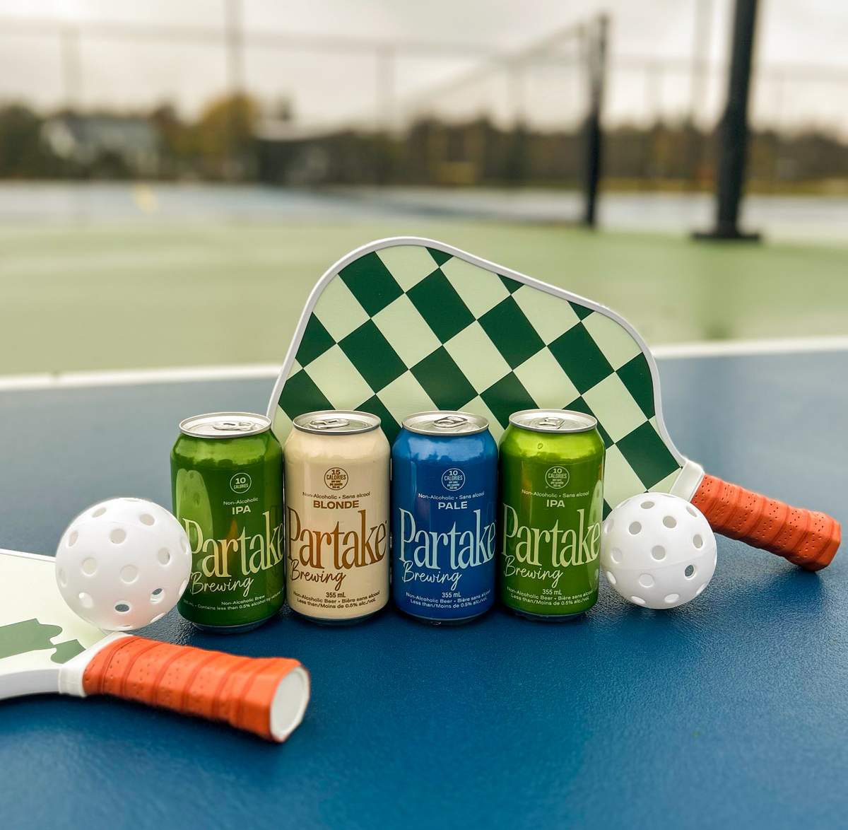 Partake Brewing beers on a pickleball court with balls and paddles 