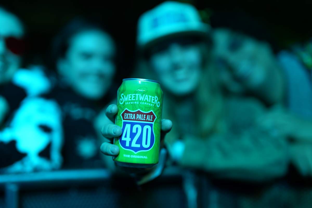 SweetWater 420 brand guy  holding can in a green dark room